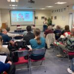 A meeting room, with attendees watching a presentation