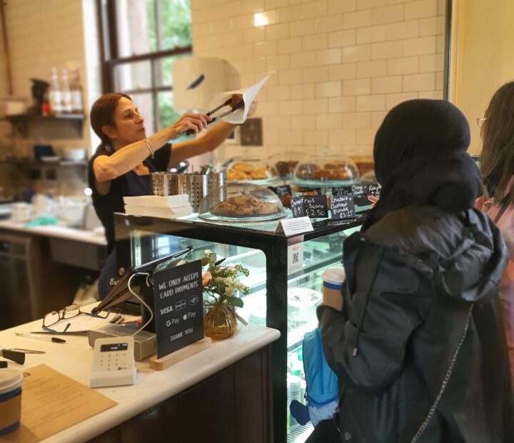 A cafe worker putting a cake in a bag for a customer