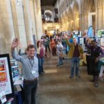 People at a community networking event in a cathedral, waving.