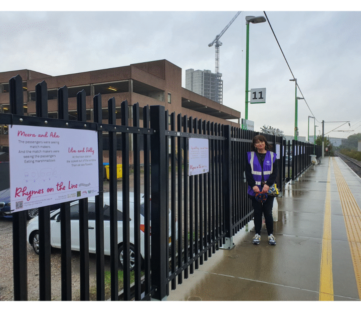 A person standing on a train platform with art works
