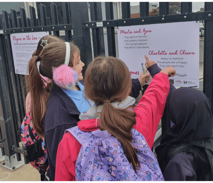 School children looking at creative work on a train platform