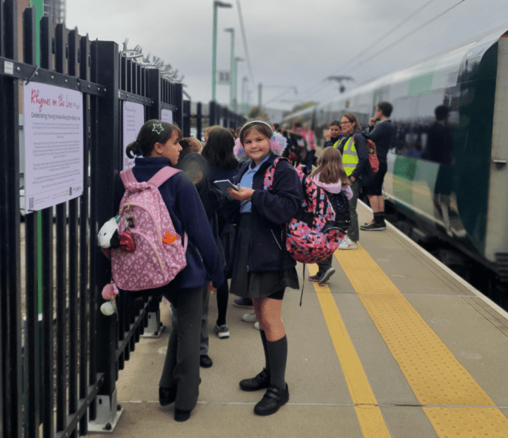 School children looking at creative work on a train platform