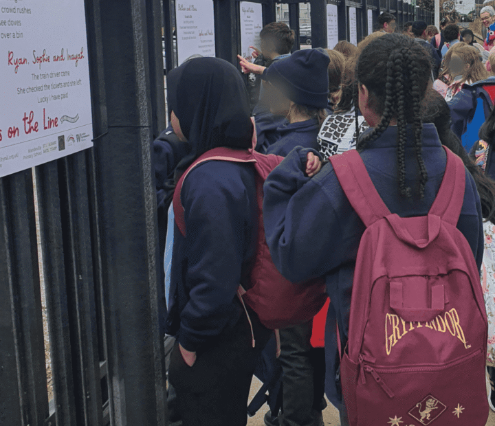 School children looking at creative work on a train platform