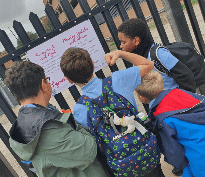 School children looking at creative work on a train platform