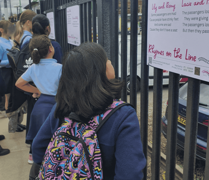 School children looking at creative work on a train platform