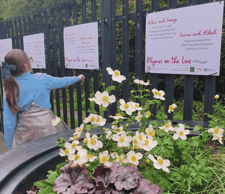 School children looking at creative work on a train platform