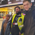 Students at a train station with a member of staff