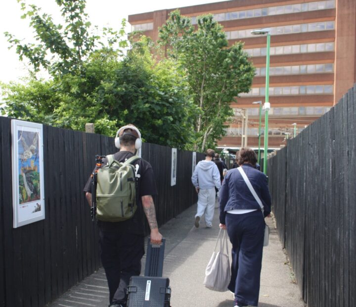 People walking past a community art exhibition at a railway station